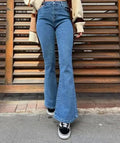 Person wearing blue jeans standing on a sidewalk with wooden steps in the background