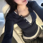Person wearing a dark blue cardigan with white buttons, sitting on a beige chair.